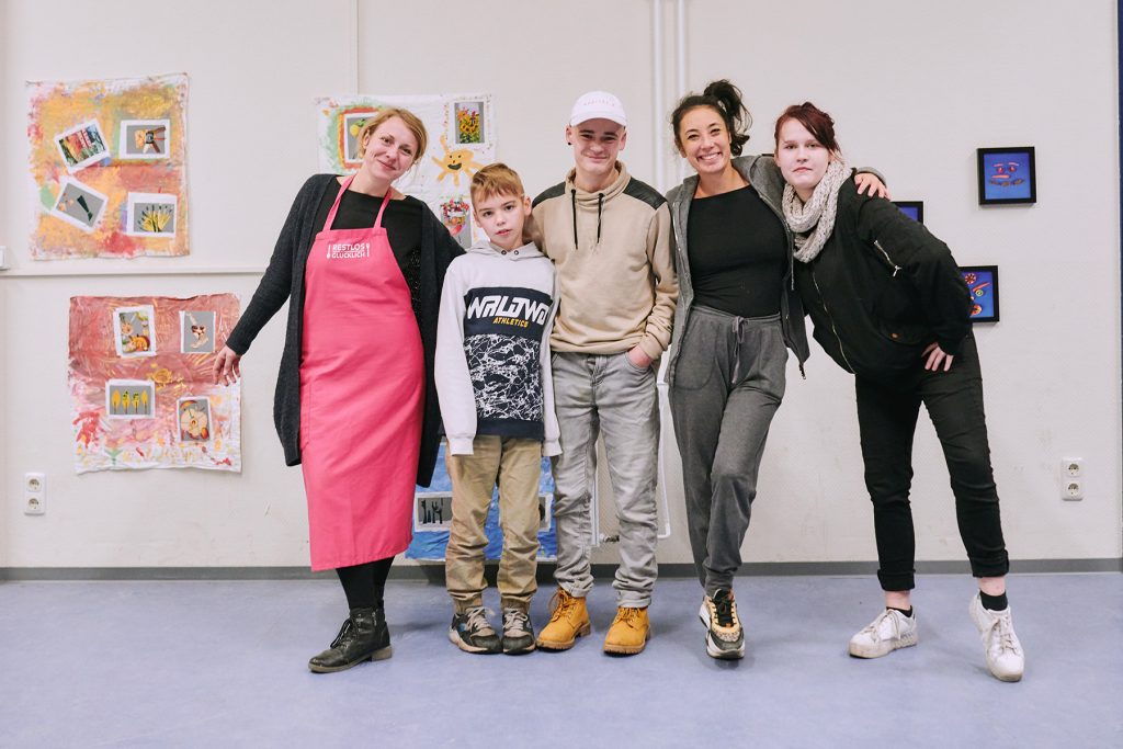 Gruppenfoto: Nina Carryer von RESTLOS GLÜCKLICH e. V. zusammen mit einem Grundschulkind und zwei erwachsenen Personen.