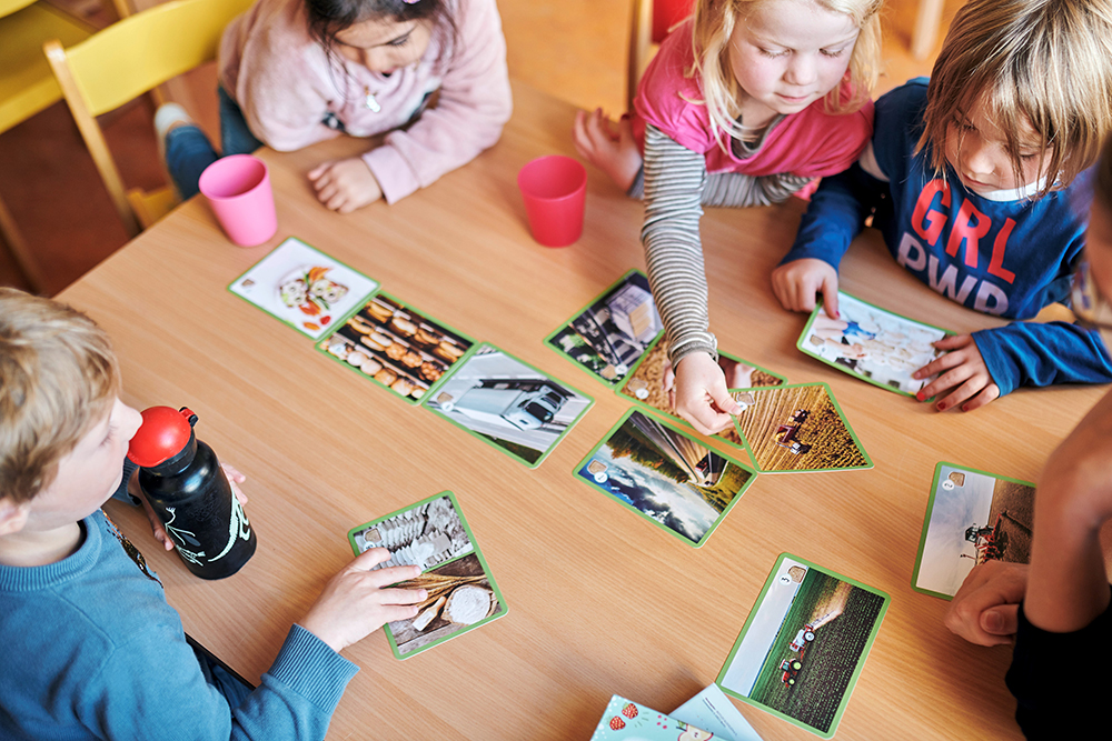 Vier Vorschulkinder sitzen an einem Tisch bei einem Bildungsspiel.