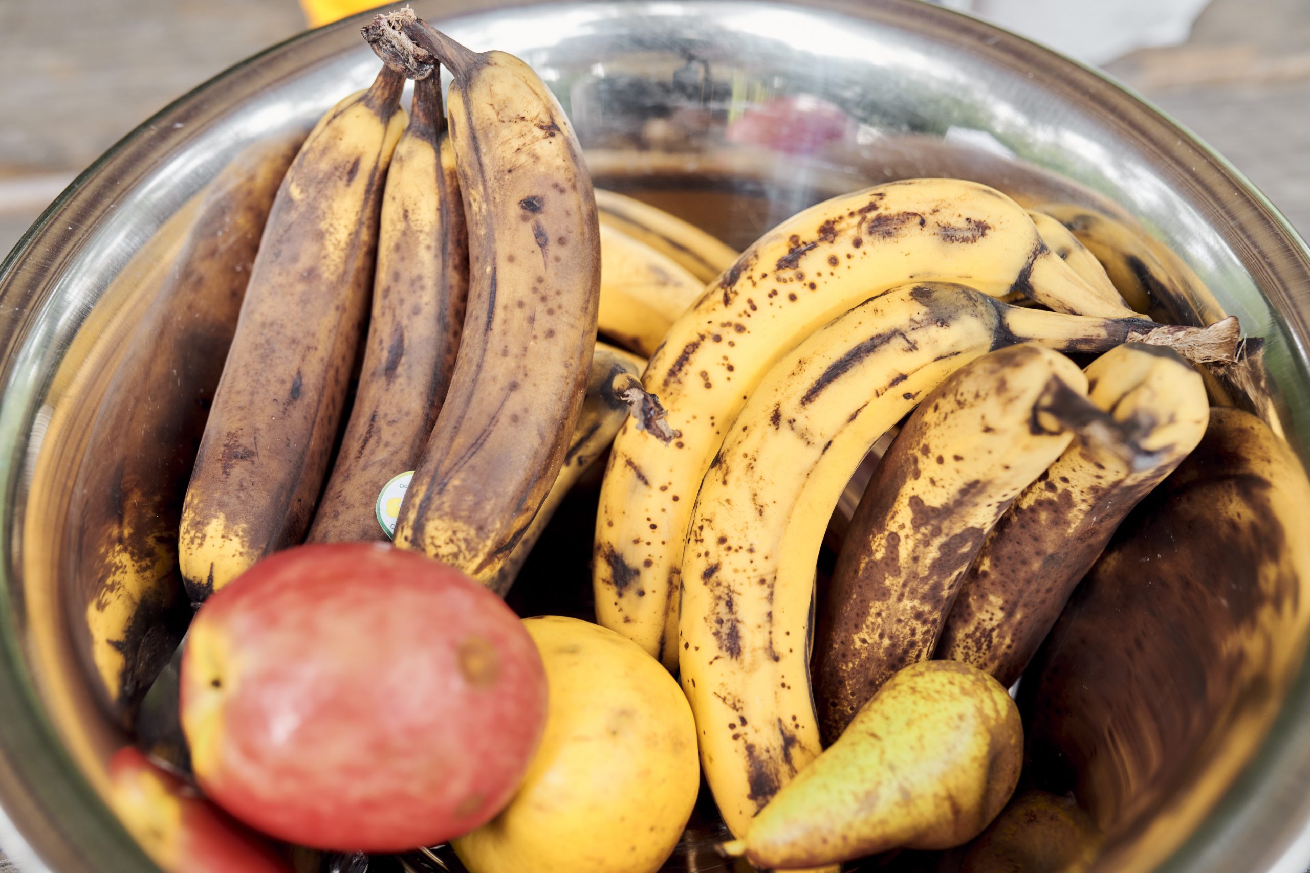 Eine Schüssel mit braunen Bananen, Äpfeln und einer Birne.