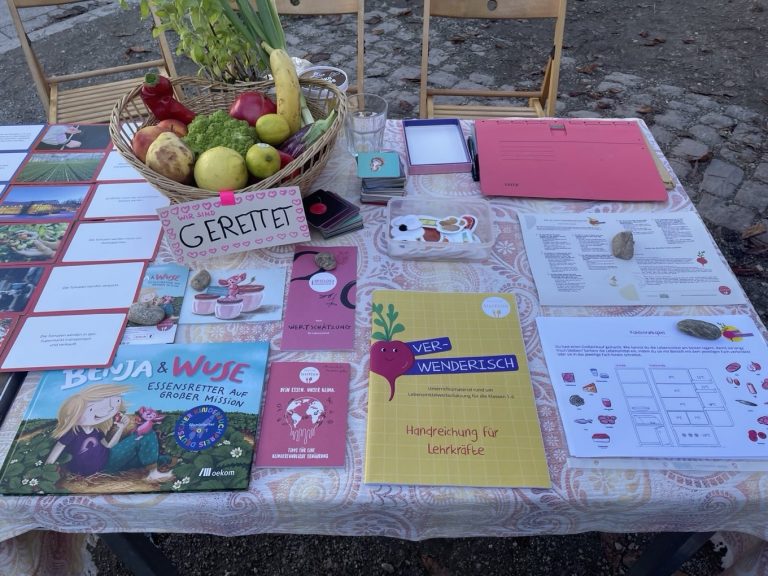 Ein Tisch eines Aktionsstand mit Bildungsmaterialien und einem Korb mit gerettetem Obst
