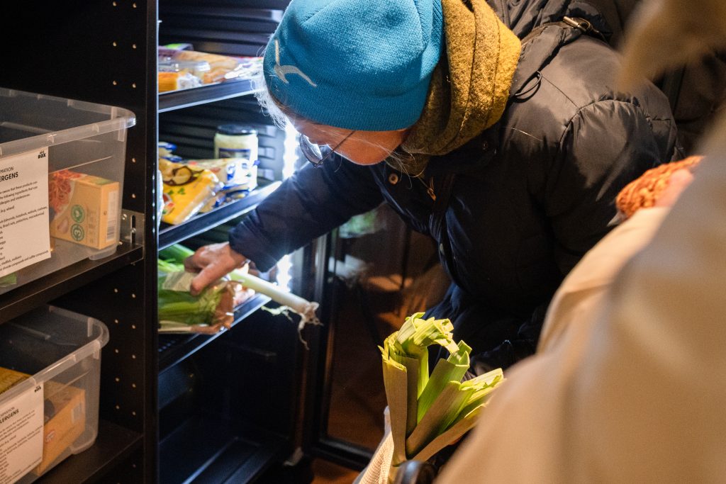 Eine Frau holt sich aus dem Kühlschrank der Verteilstation, auch Kiezbox genannt, Lebensmittel, die sie gebrauchen kann.