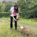 Eine Mitarbeiterin von RESTLOS GLÜCKLICH gräbt mit einem Spaten in der Erde.