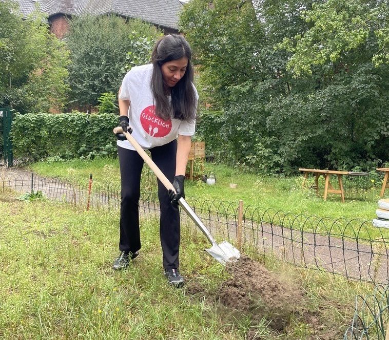 Eine Mitarbeiterin von RESTLOS GLÜCKLICH gräbt mit einem Spaten in der Erde.