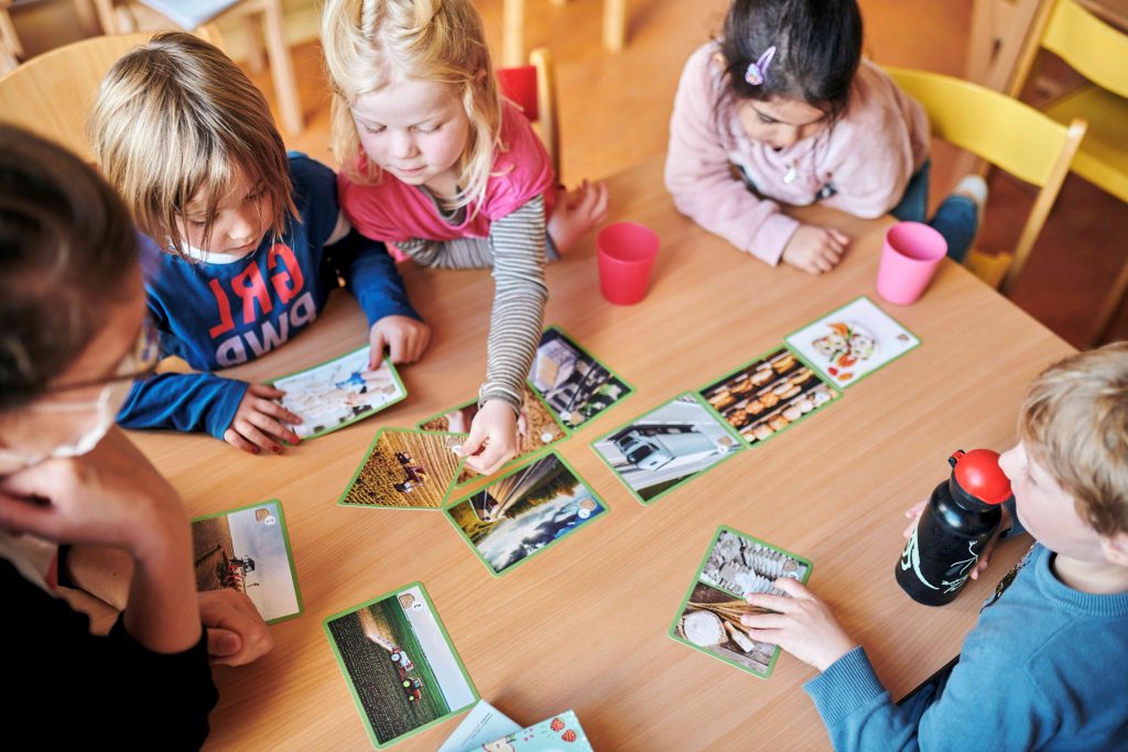 Drei Vorschulkinder spielen ein Bildungspiel an einem Tisch im Kindergarten.