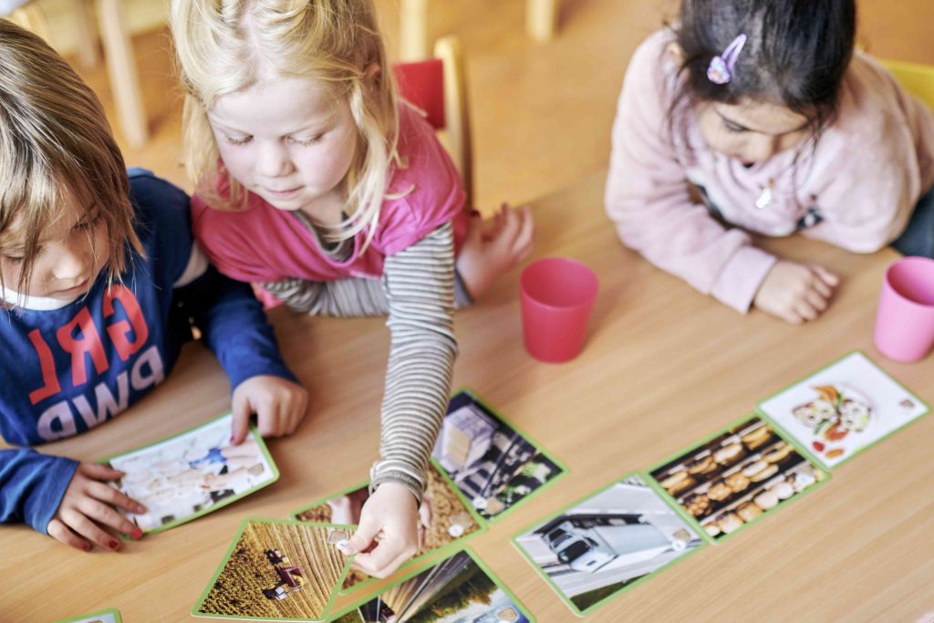 Drei Vorschulkinder spielen ein Bildungspiel an einem Tisch im Kindergarten.
