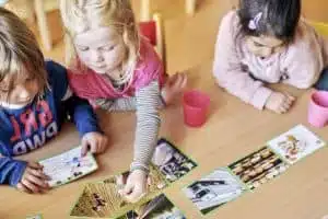 Drei Vorschulkinder spielen ein Bildungspiel an einem Tisch im Kindergarten.