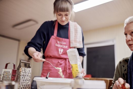 Ramona Holzer von RESTLOS GLÜCKLICH e. V. gibt mit einem Löffel Mehl aus einer Mehltüte in eine Schüssel